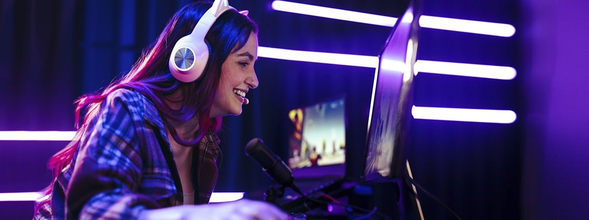 Streamer broadcasting gameplay with microphone, camera and dual monitors