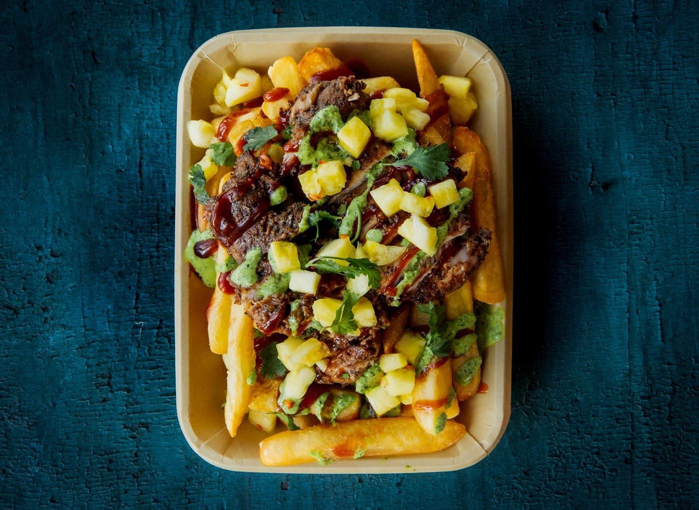 Loaded jerk chicken fries topped with mango salsa