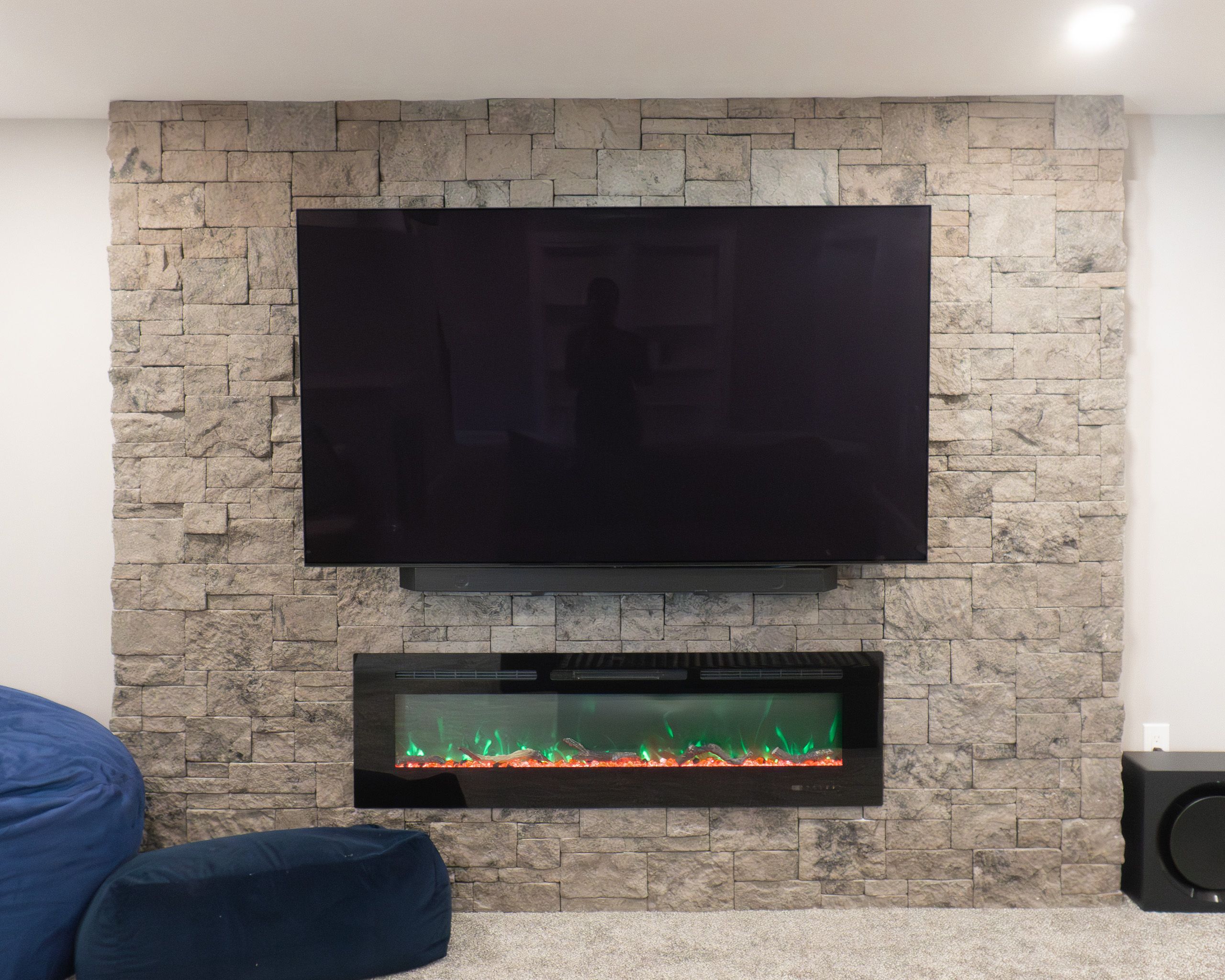 The TV above a fireplace on a faux stone wall