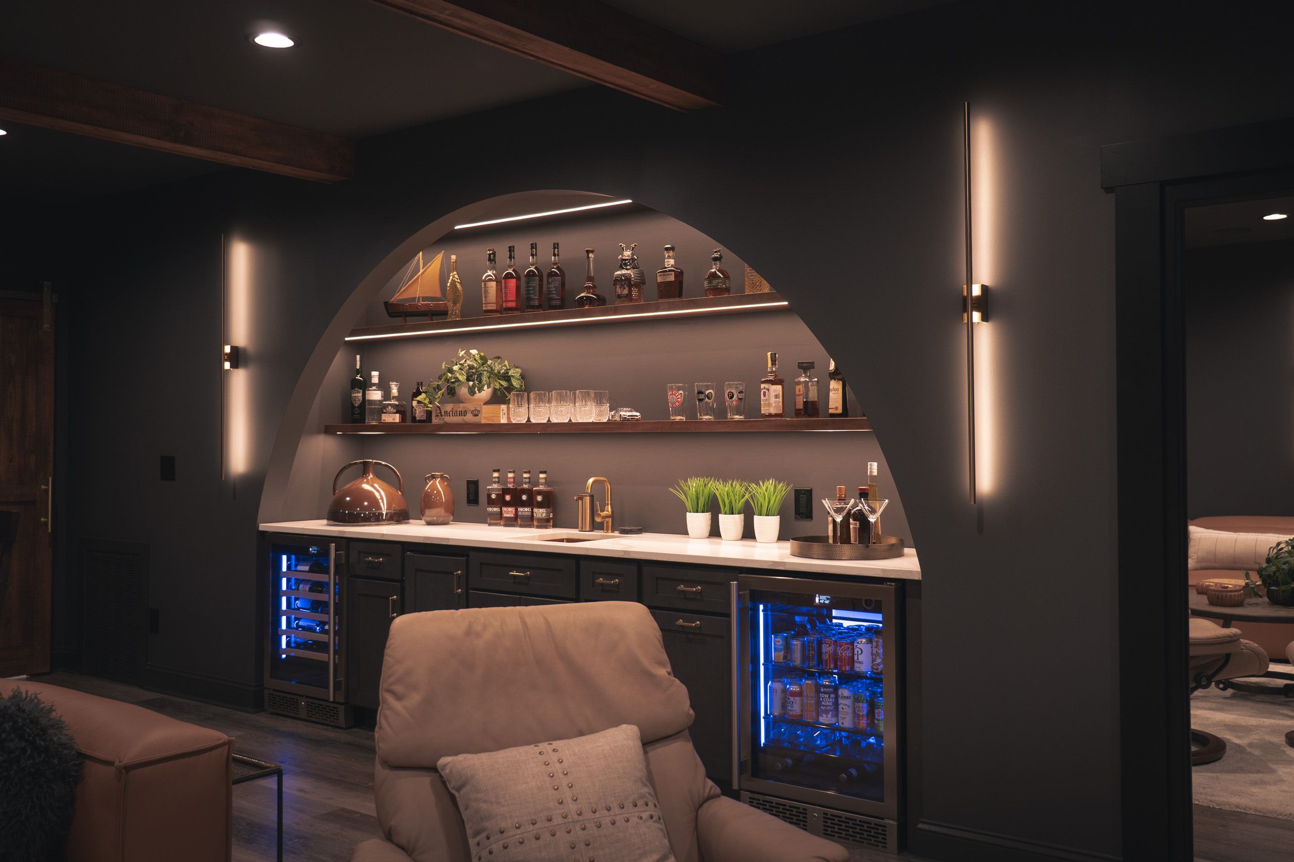 Arched wet bar with floating shelves filled with whiskey bottles