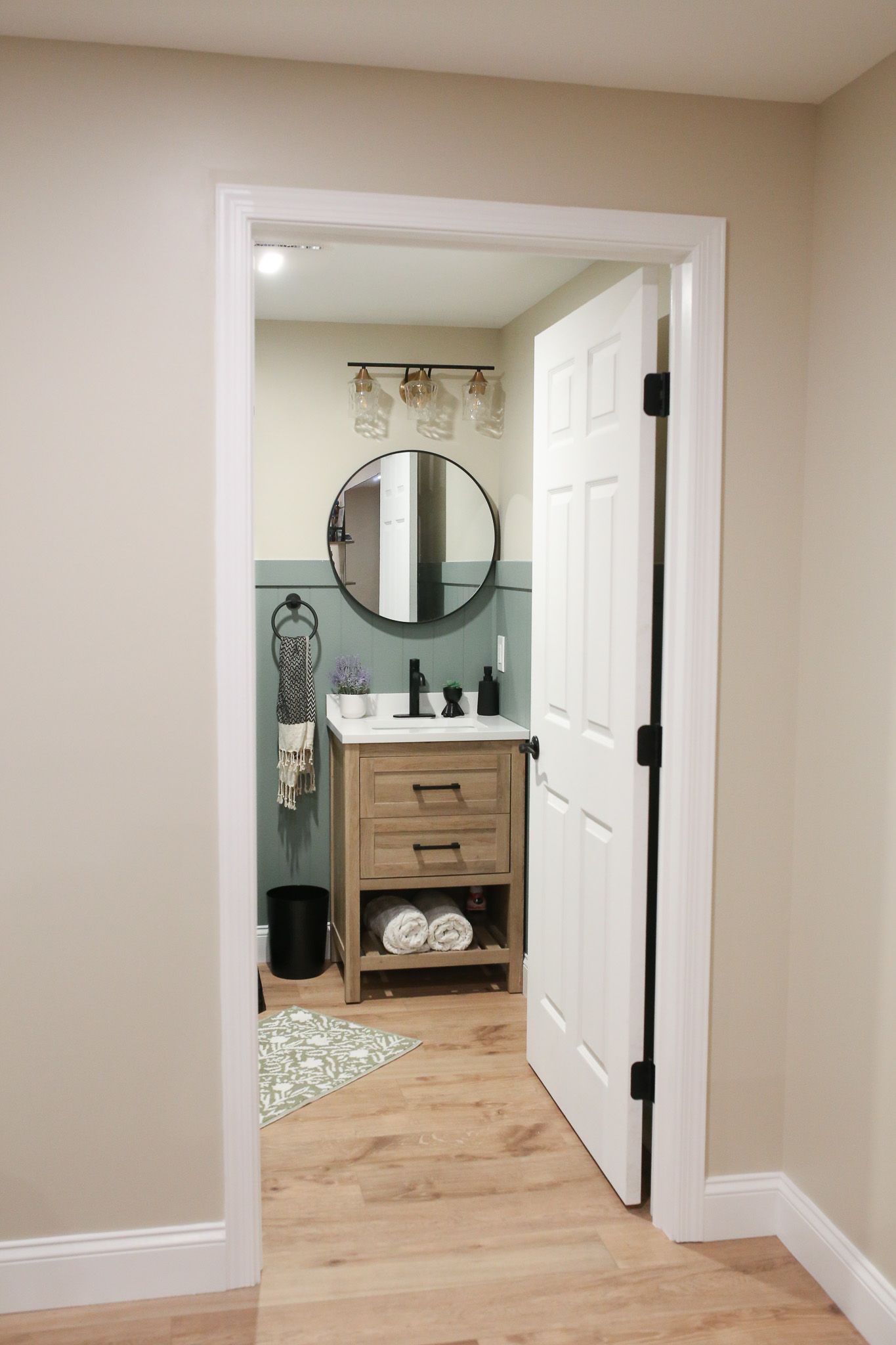 bathroom with a wooden vanity and round mirror above it