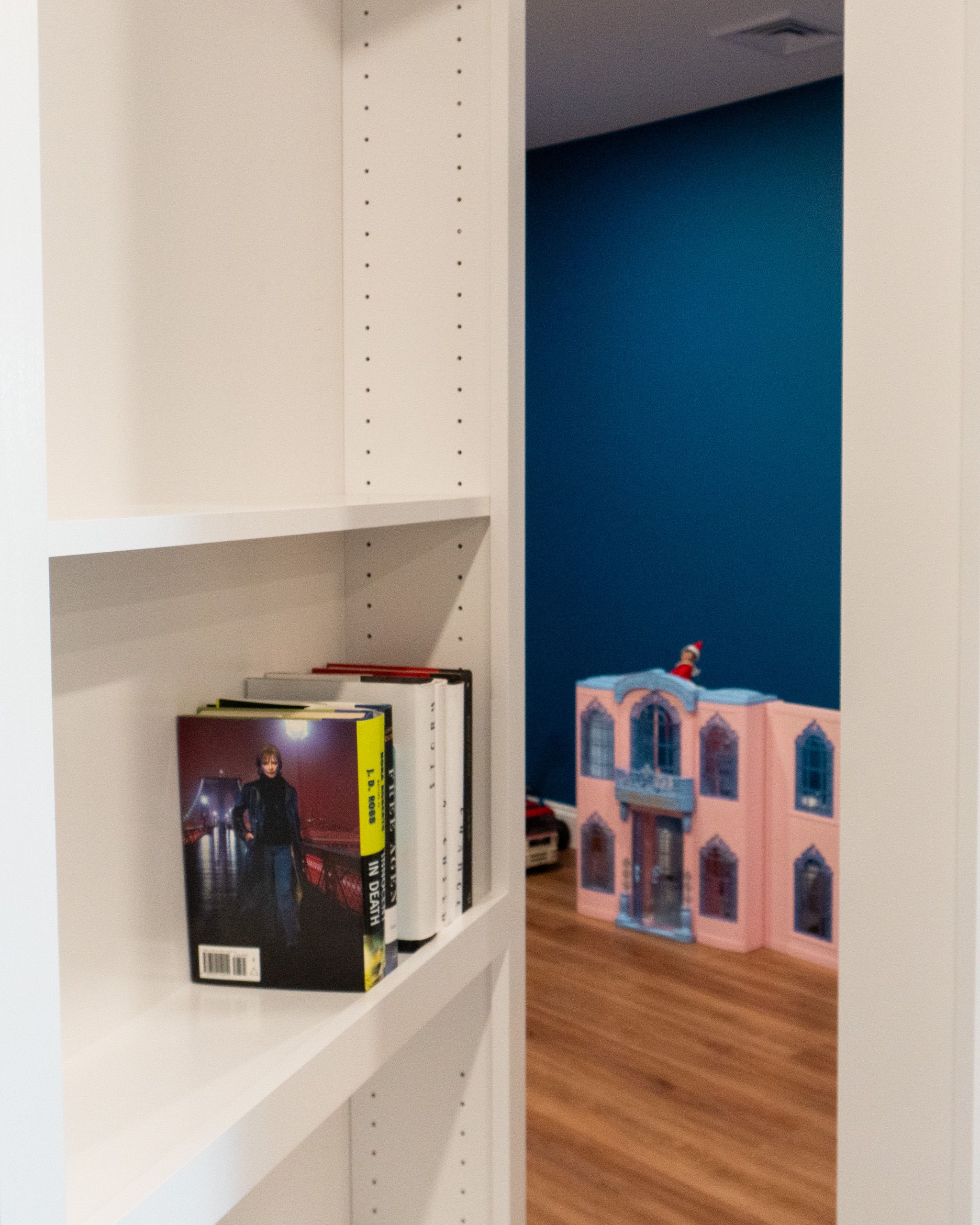 Slightly cracked bookshelf Murphy Door® showing a doll house in the playroom