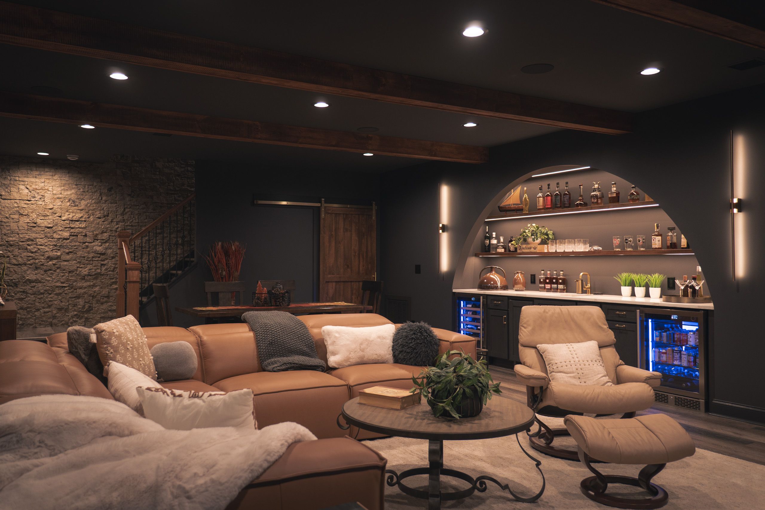 Dark, moody basement with leather couches and a wet bar