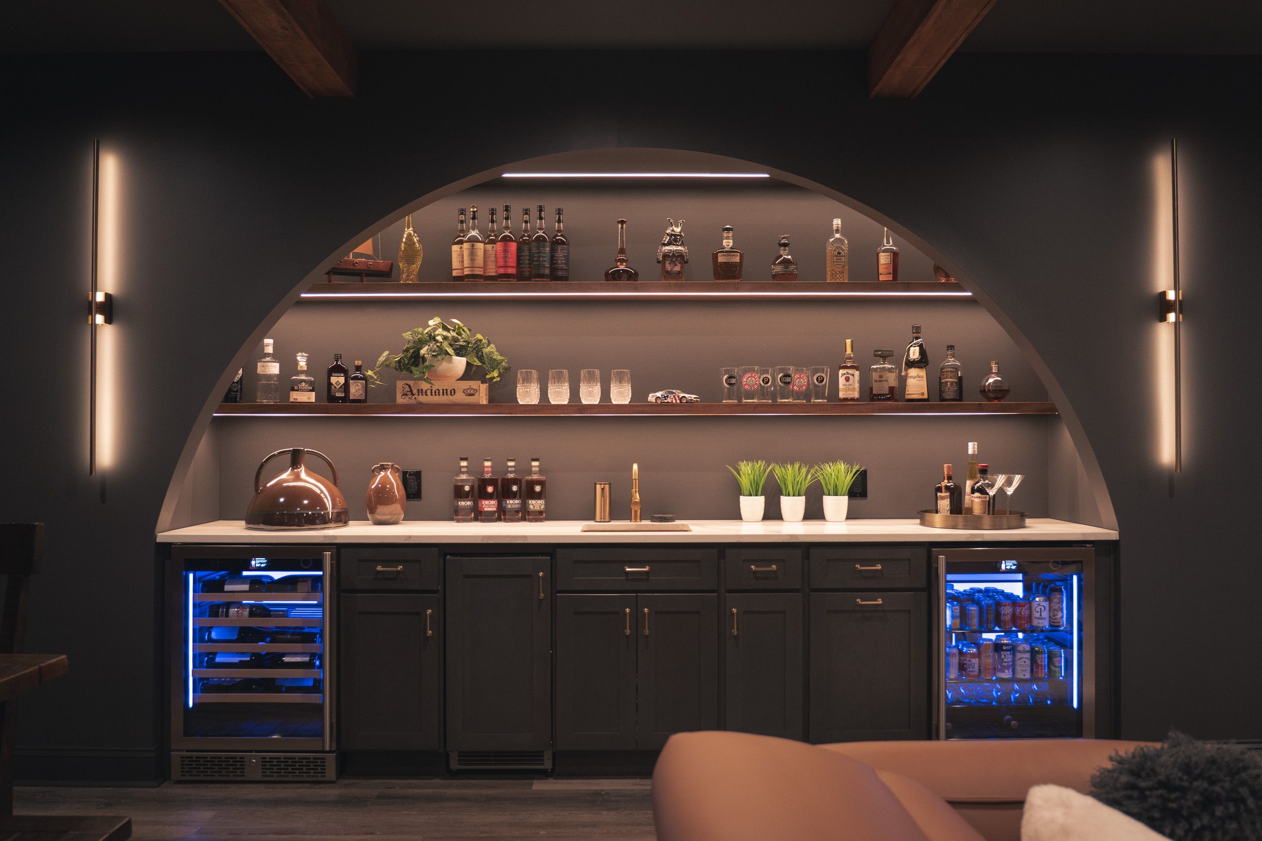 Arched wet bar with floating shelves filled with whiskey bottles