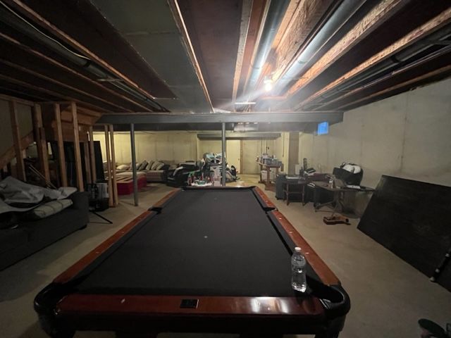 pool table in a cluttered unfinished basement