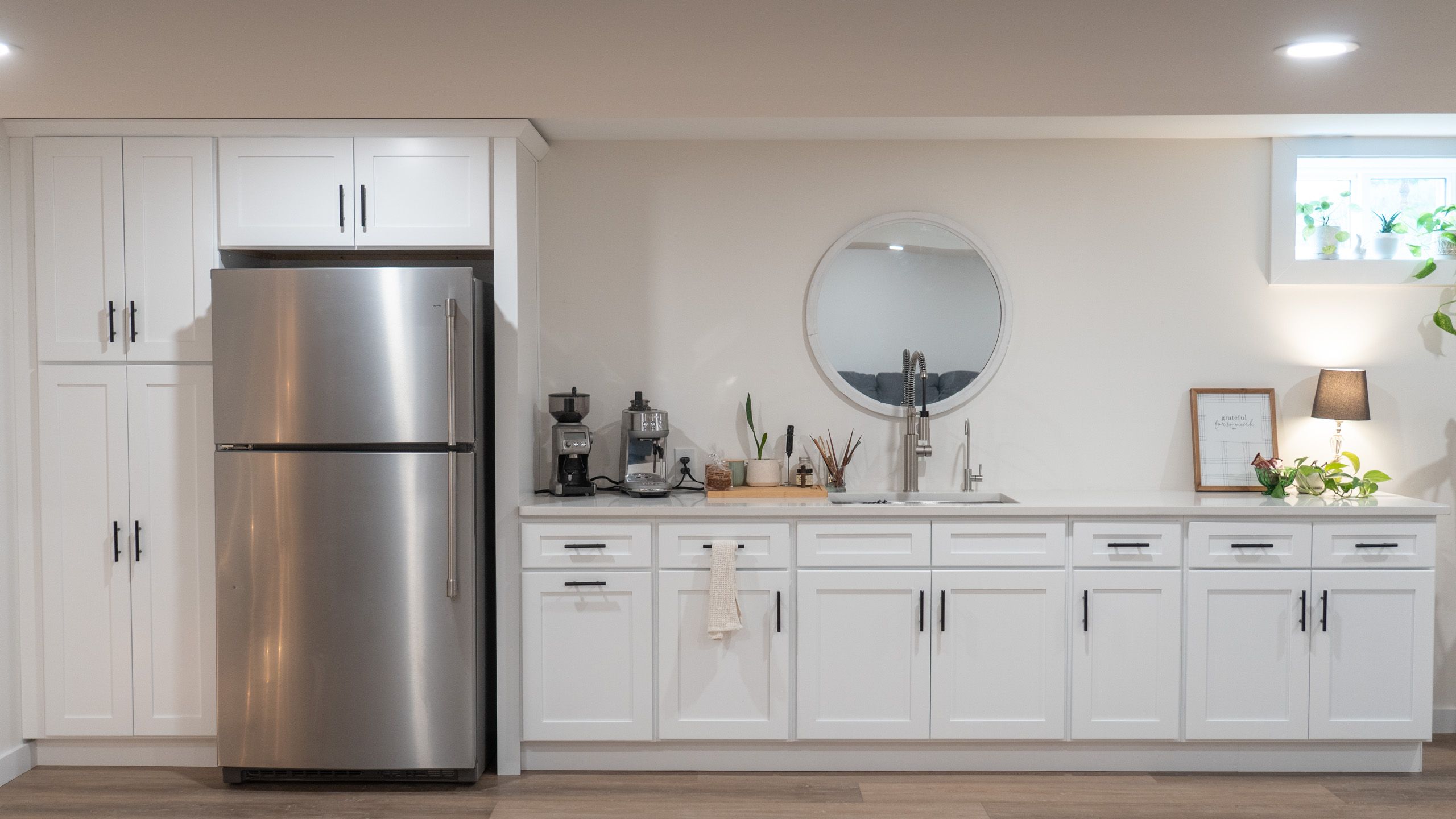Wet bar with white cabinets in newly finished basement