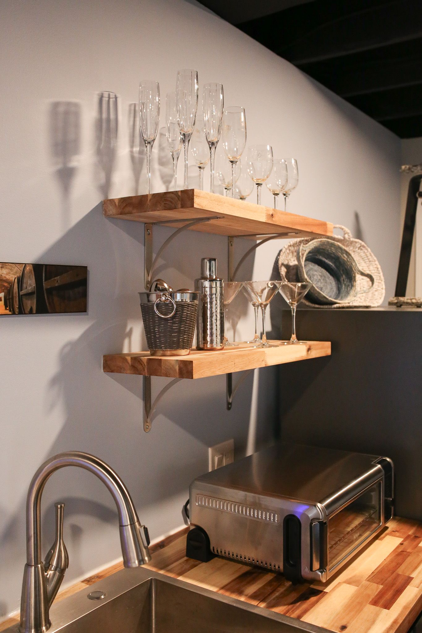 floating shelves above wet bar with wine glasses and drink mixer