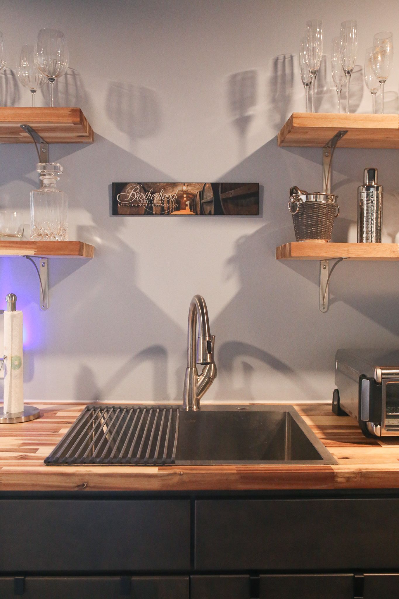 basement wet bar sink with floating shelves on each side