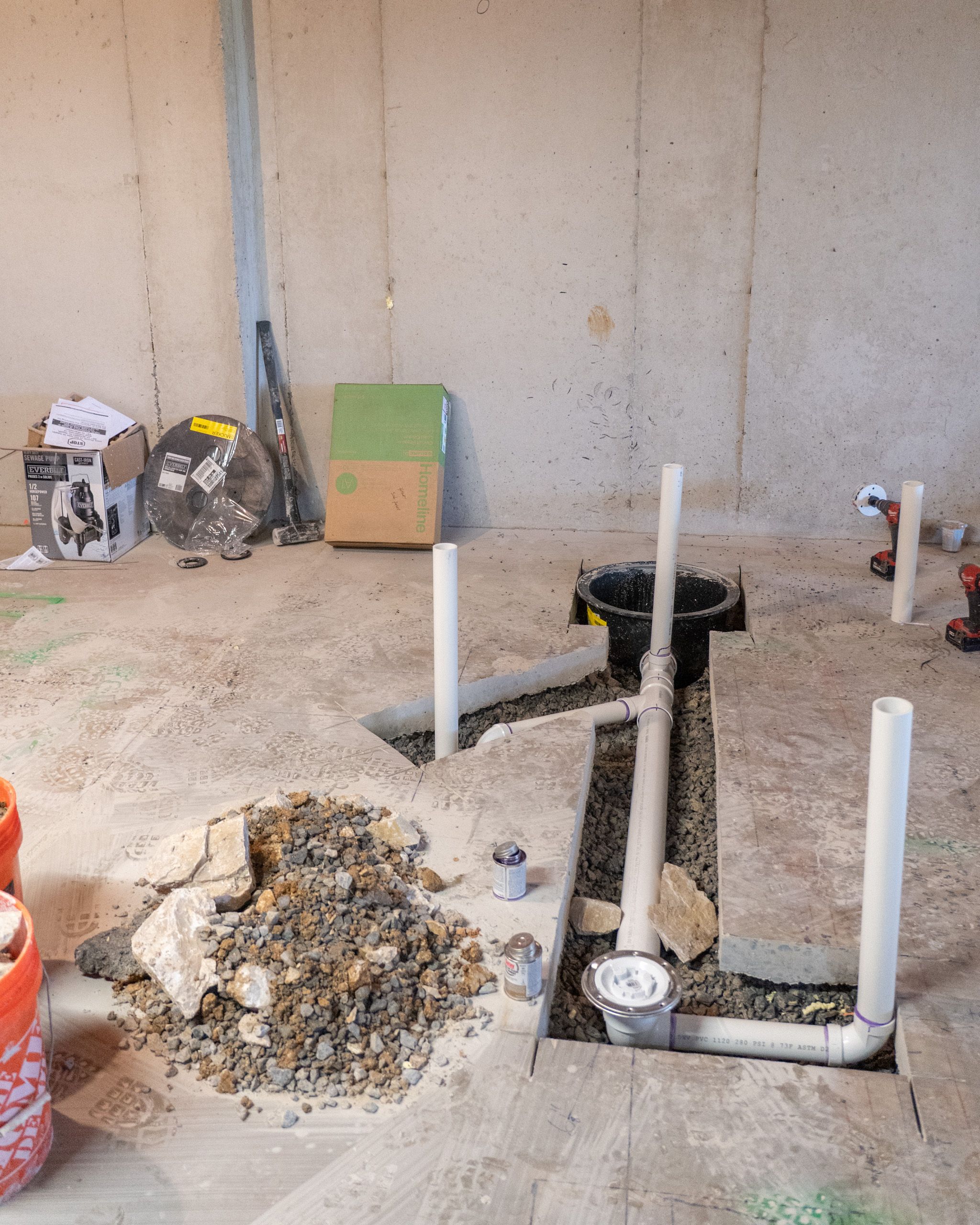 Grinder pit and under-slab plumbing for basement remodel