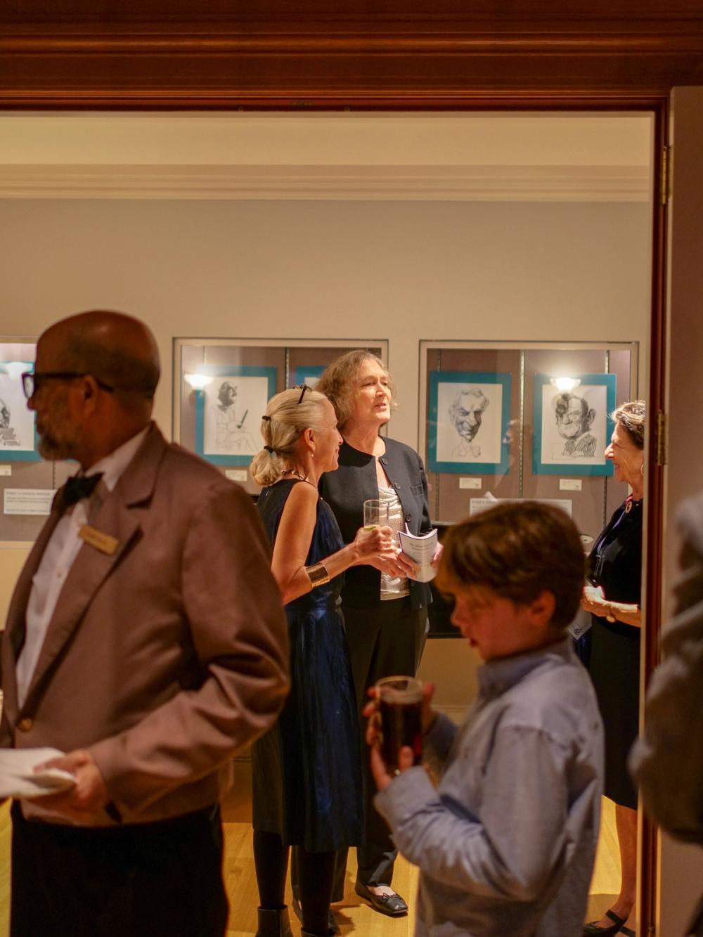 A photo of two women standing in the distance. Closest to the camera is Erika, who is wearing a blue dress. Wendy stands behind her in a black jacket.