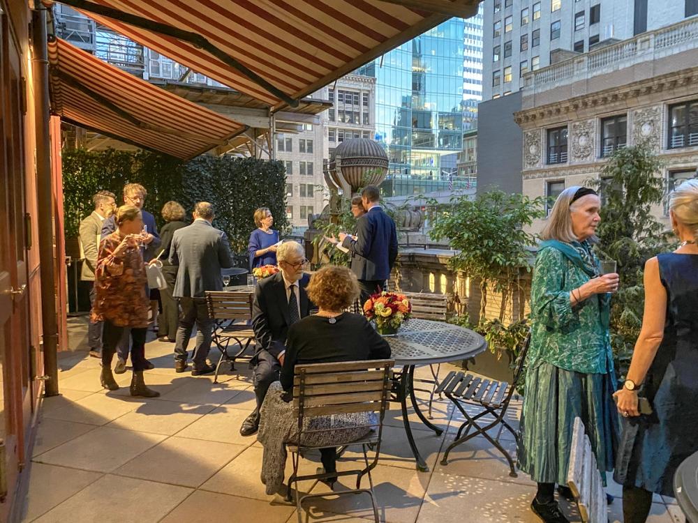 A photo of several people in conversation on an outdoor patio in Manhattan.