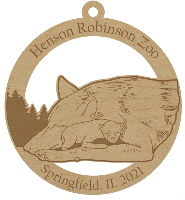 Round natural wood ornament laser engraved with a sleeping wolf and cub, a tree line, the zoo's name and the year