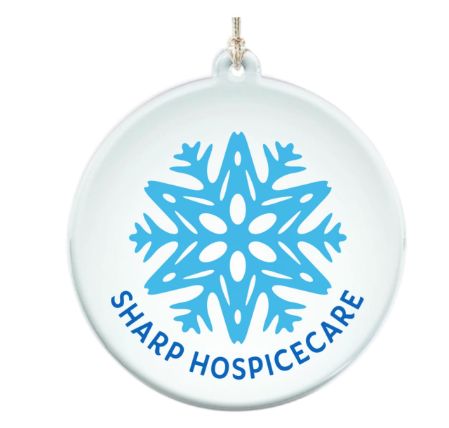 Clear round acrylic ornament printed with a light blue snowflake and the organization's name curved in dark blue below it, hung on a gold cord