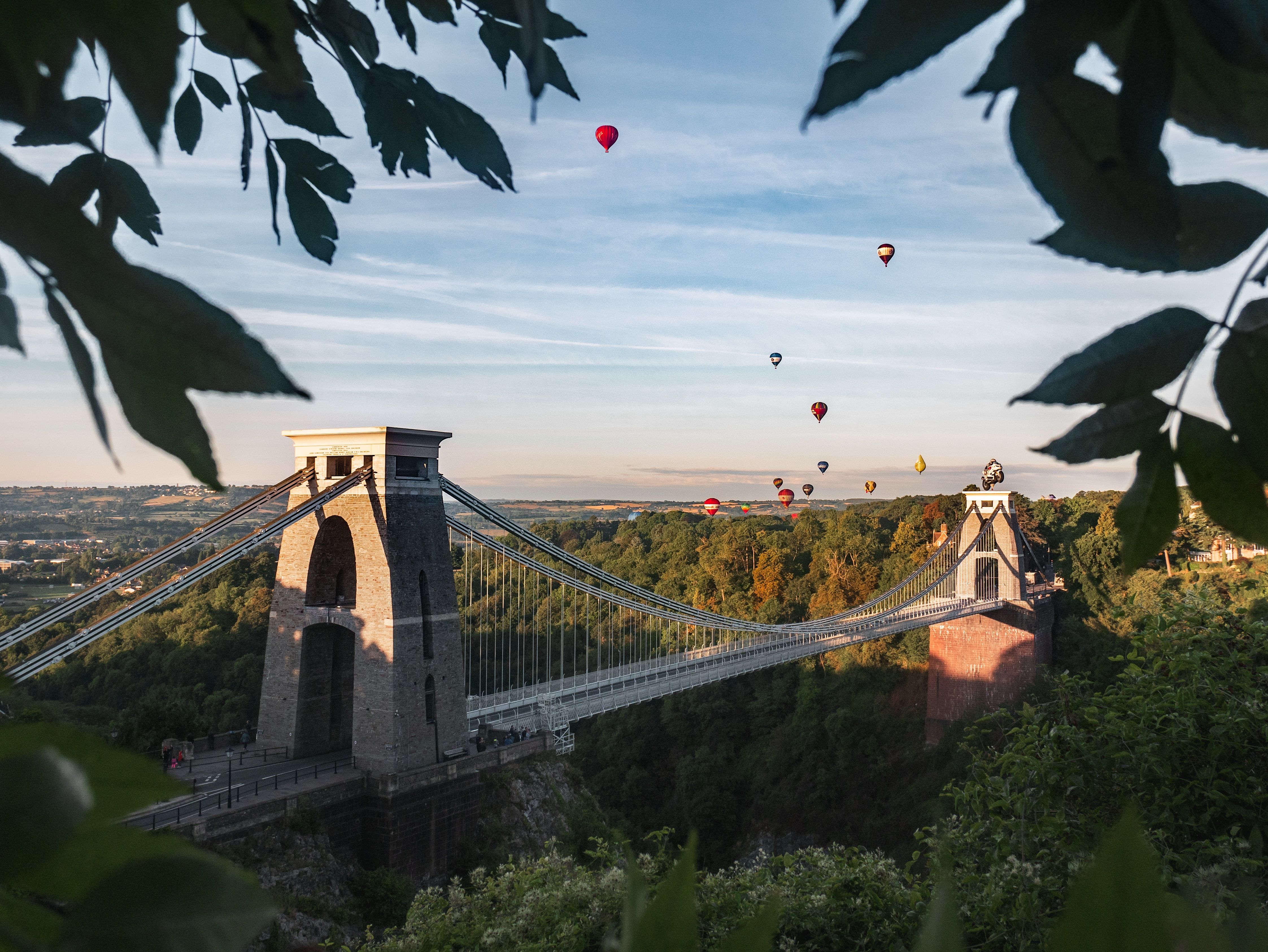 The Clifton Suspension Bridge spanning the Avon Gorge, with hot air balloons overhead