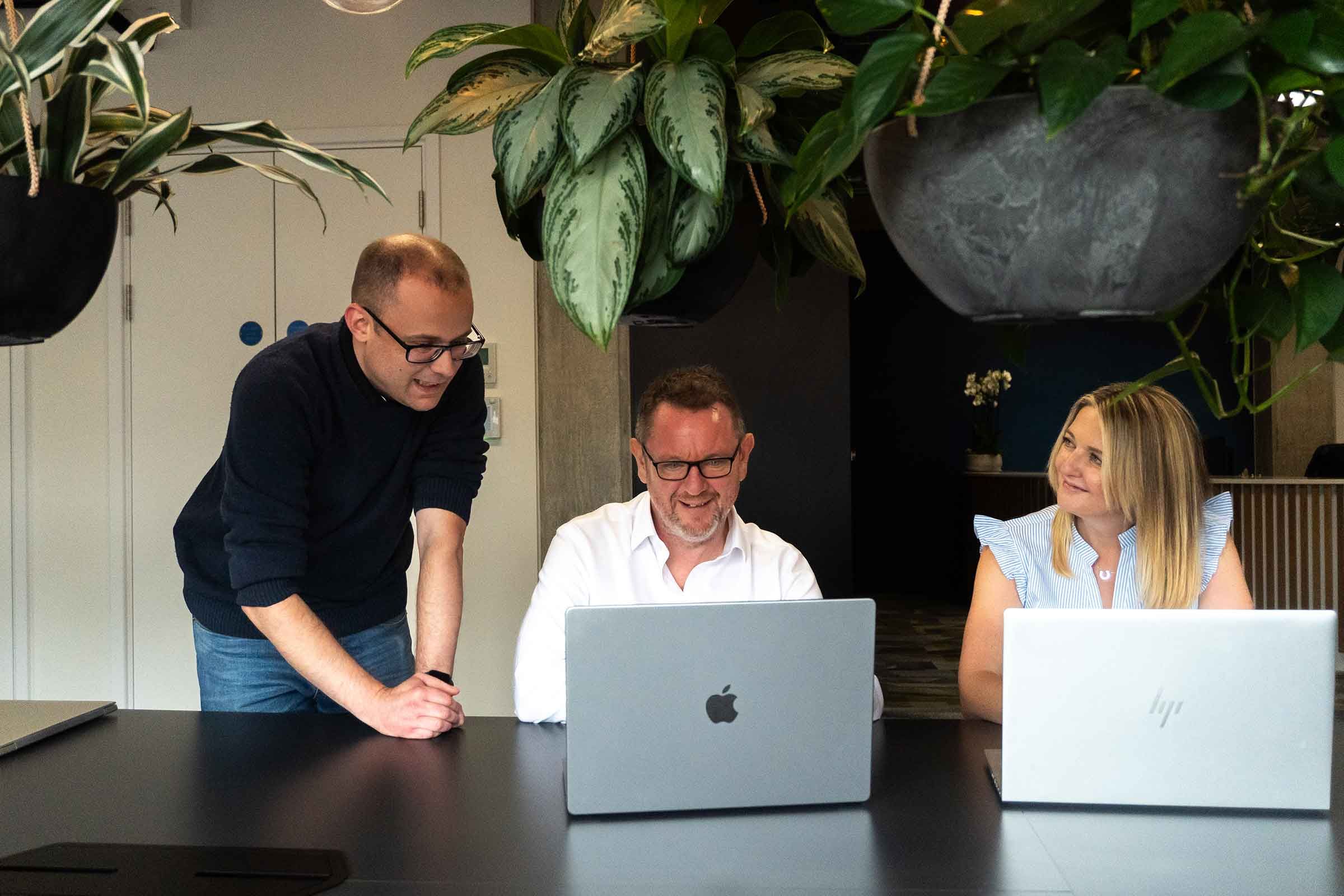 Two Inflection Point colleagues at a laptop, one leaning in to help