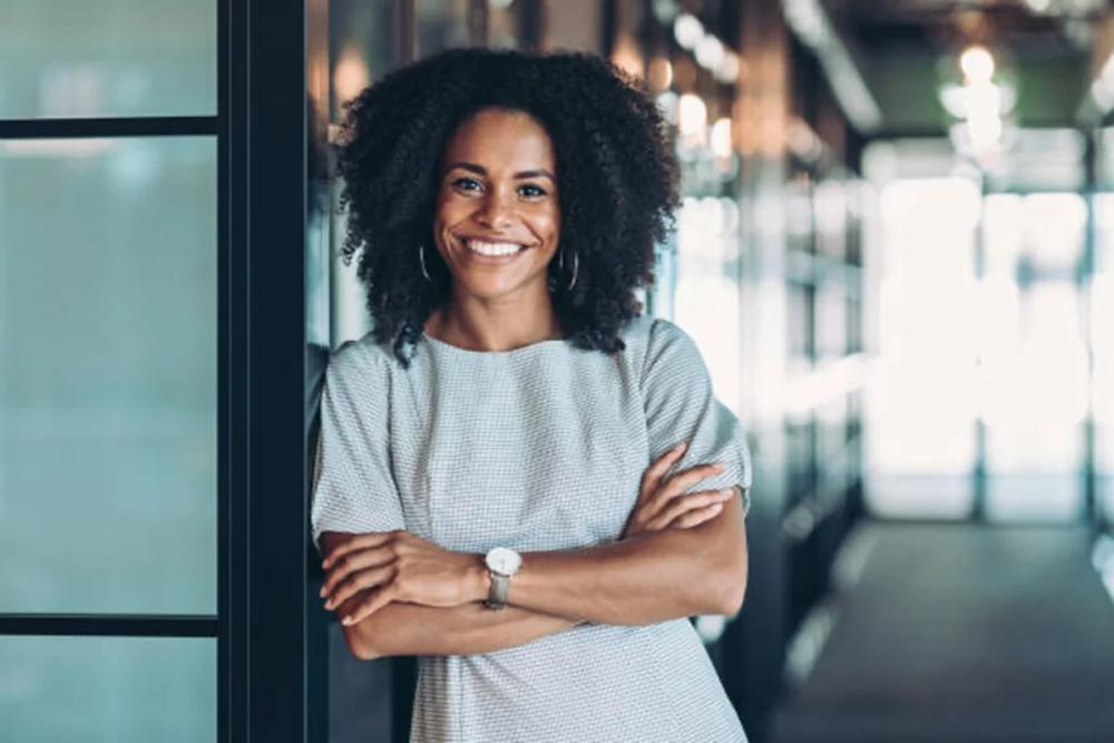 Confident professional woman standing with folded arms in a modern office
