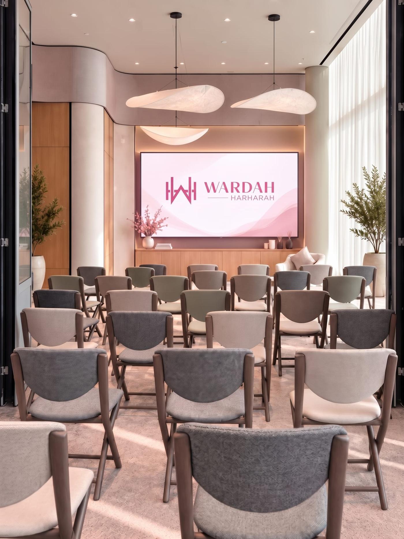 An empty seminar room, rows of upholstered chairs facing a screen