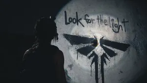A silhouette of Ellie shining her flashlight on a wall with some spraypainted graffiti. It’s the Firefly symbol with the words "Look for the light".