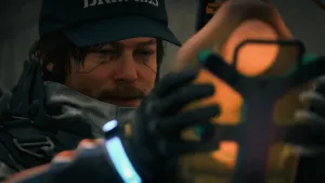A close up of Sam holding up Lou’s BB unit and smiling. Sam’s face is lit warmly by the glow of the BB unit.