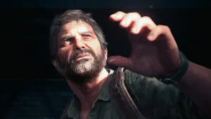 A close up of Joel squinting up and shielding his eyes from the sun.