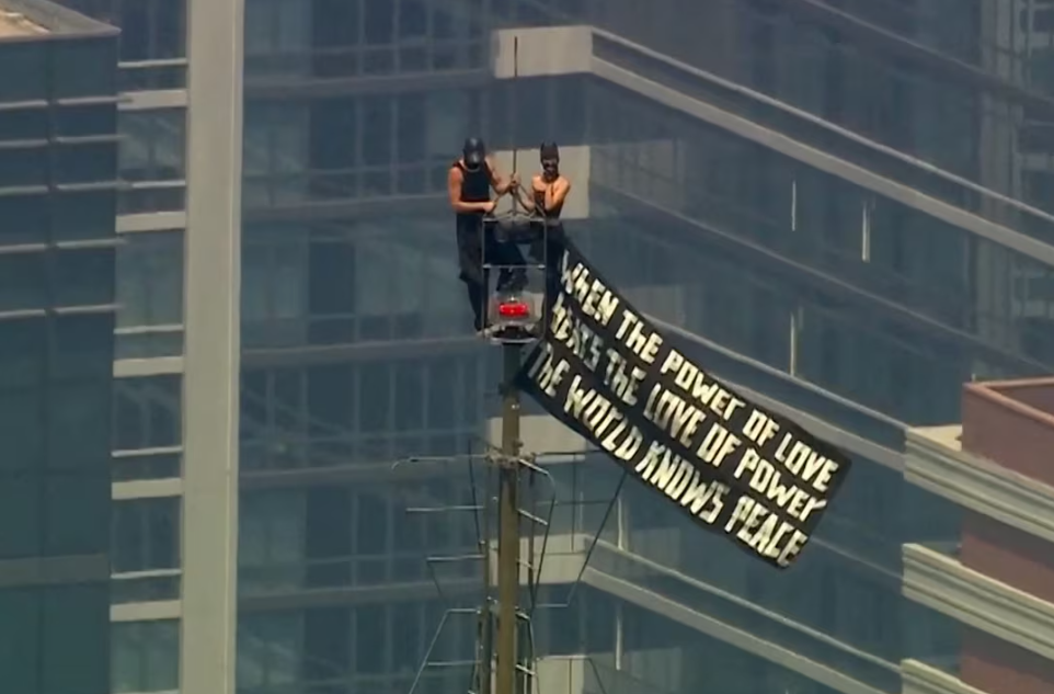 The Empire State Building banner proposal as the couple displays a banner from the building's restricted spire overlooking the New York City skyline.