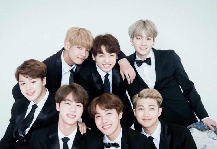 A high-quality photo of all seven members of BTS standing together smiling at a global music award show.
