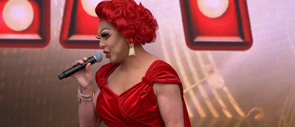 La Voix performing on stage in a glamorous outfit while singing in front of a live audience