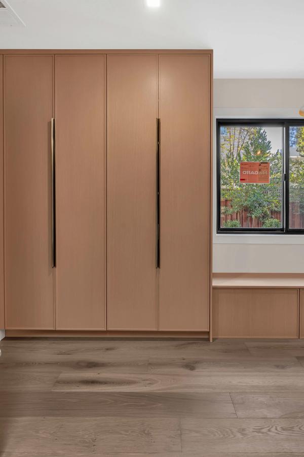 Walk-in closet, full-height white oak cabinetry with LED-lit shelving and hanging rails