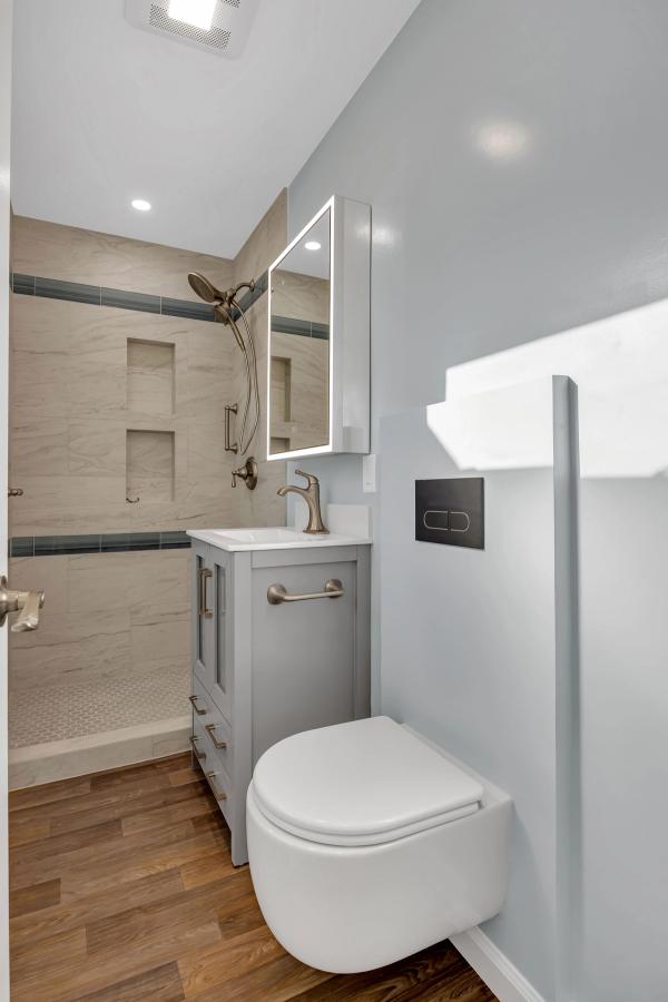 Bathroom, wider view with wall-mounted toilet and LED mirror