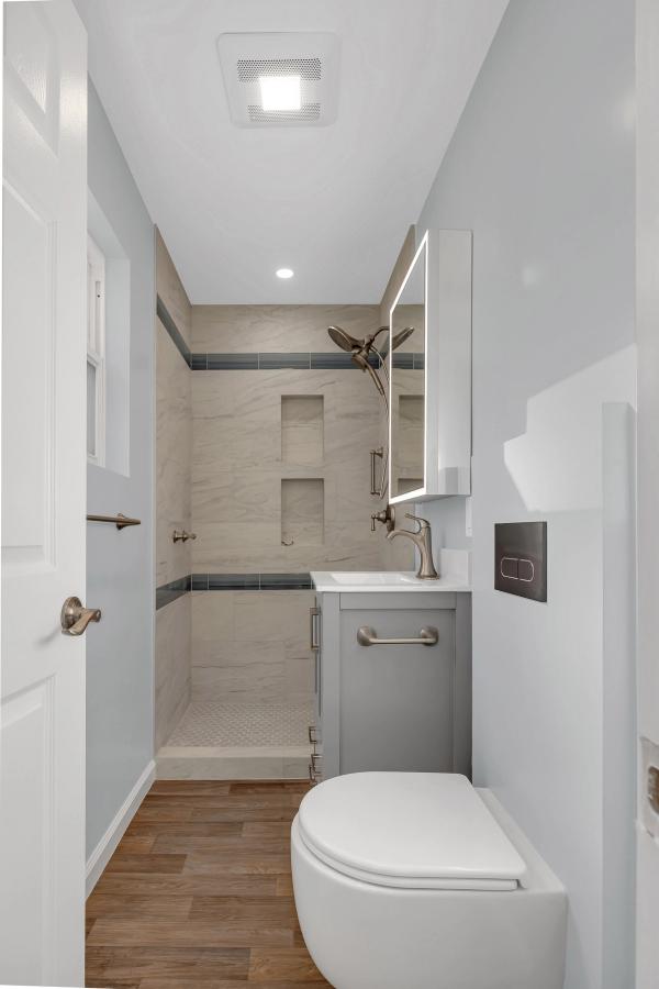 Bathroom at 2065 Fiesta Ct, full view with gray vanity, LED mirror, marble tile shower, and wall-mounted toilet