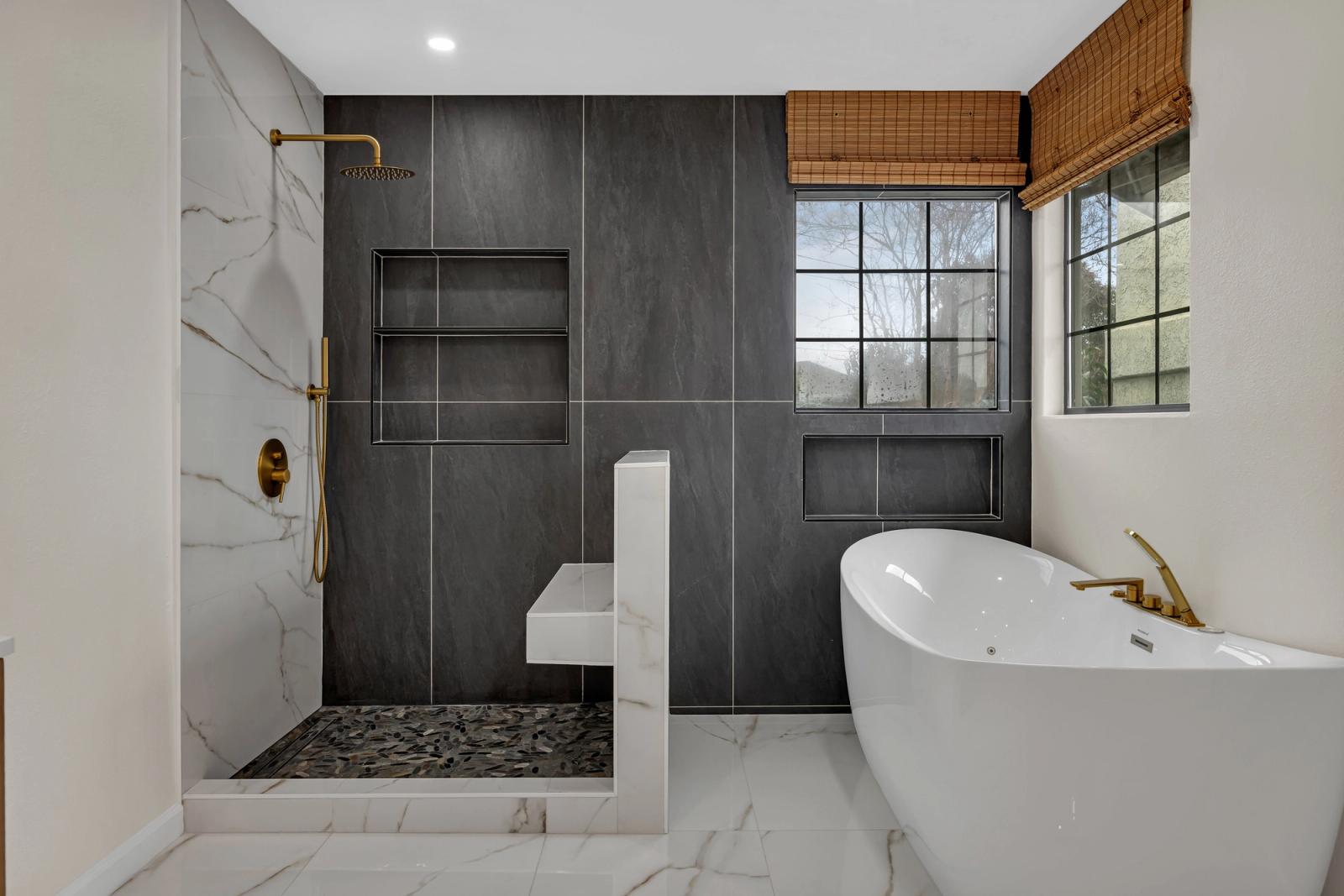 Dark slate feature wall with freestanding tub and gold fixtures