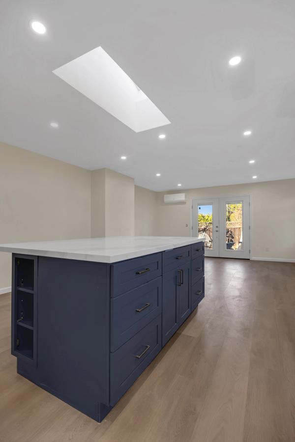 Kitchen, island detail with skylight and French doors to backyard