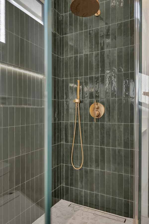 Master bath, brushed gold shower fixtures closeup on green glazed tile