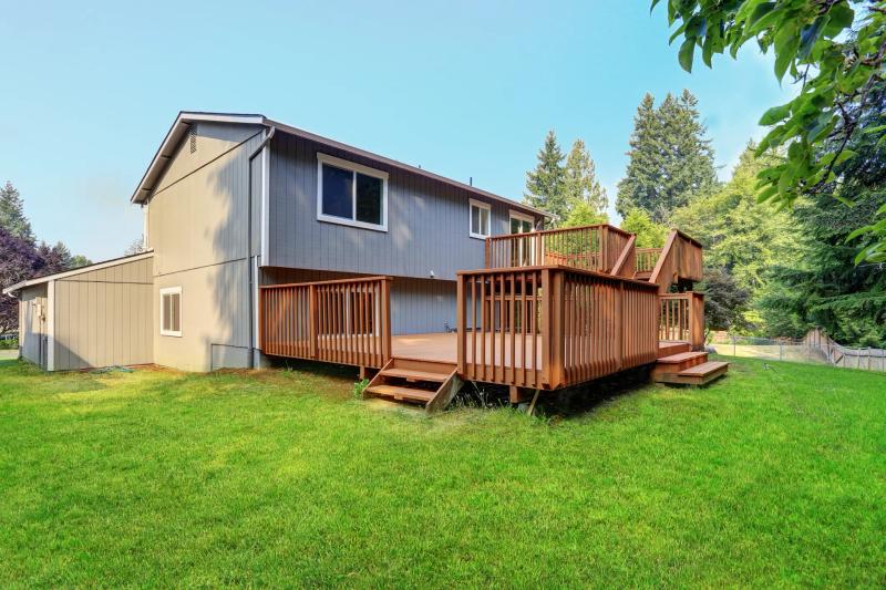 Two-level wood deck with stairs — Peninsula home with sloped backyard