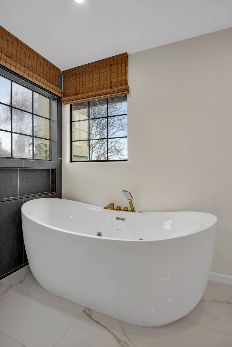 Freestanding soaking tub with gold fixtures and bamboo window blinds — Redwood City luxury bathroom