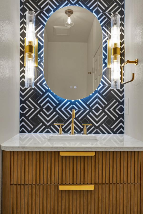Powder room at Chestwood Dr, geometric black and white tile with fluted oak vanity and crystal sconces