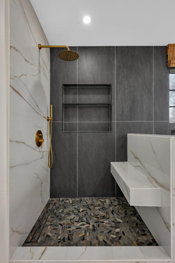 Shower niche and pebble floor closeup with gold hardware