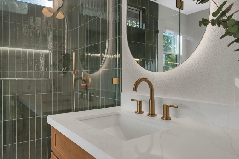 Master bath, vanity junction detail with brass faucet and backlit mirror