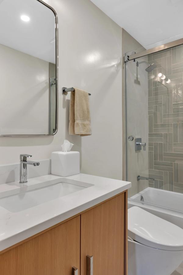 Hall bath, oak vanity with quartz top and basketweave tile tub surround