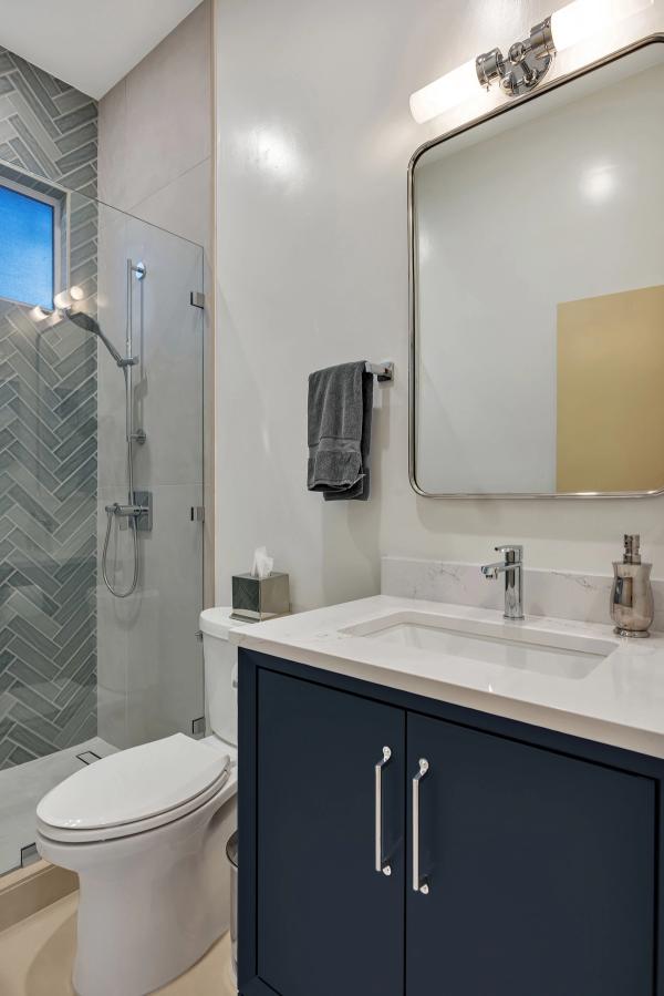 Guest bath, navy vanity with quartz top and herringbone shower