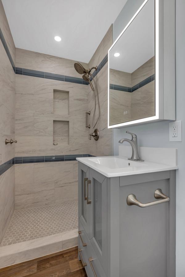 Bathroom, vanity and LED mirror with walk-in shower visible