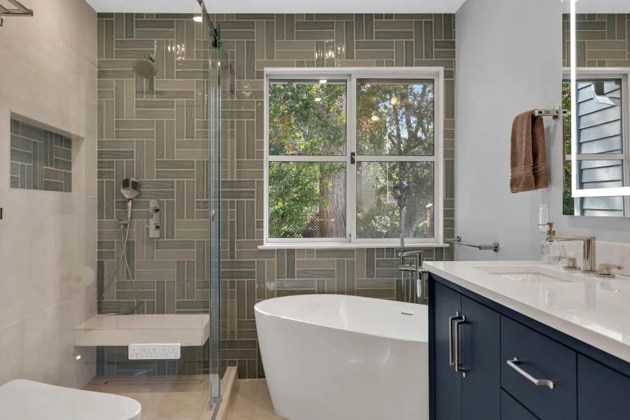 Finished white zellige tile shower with marble bench and gold fixtures — properly waterproofed before tile installation
