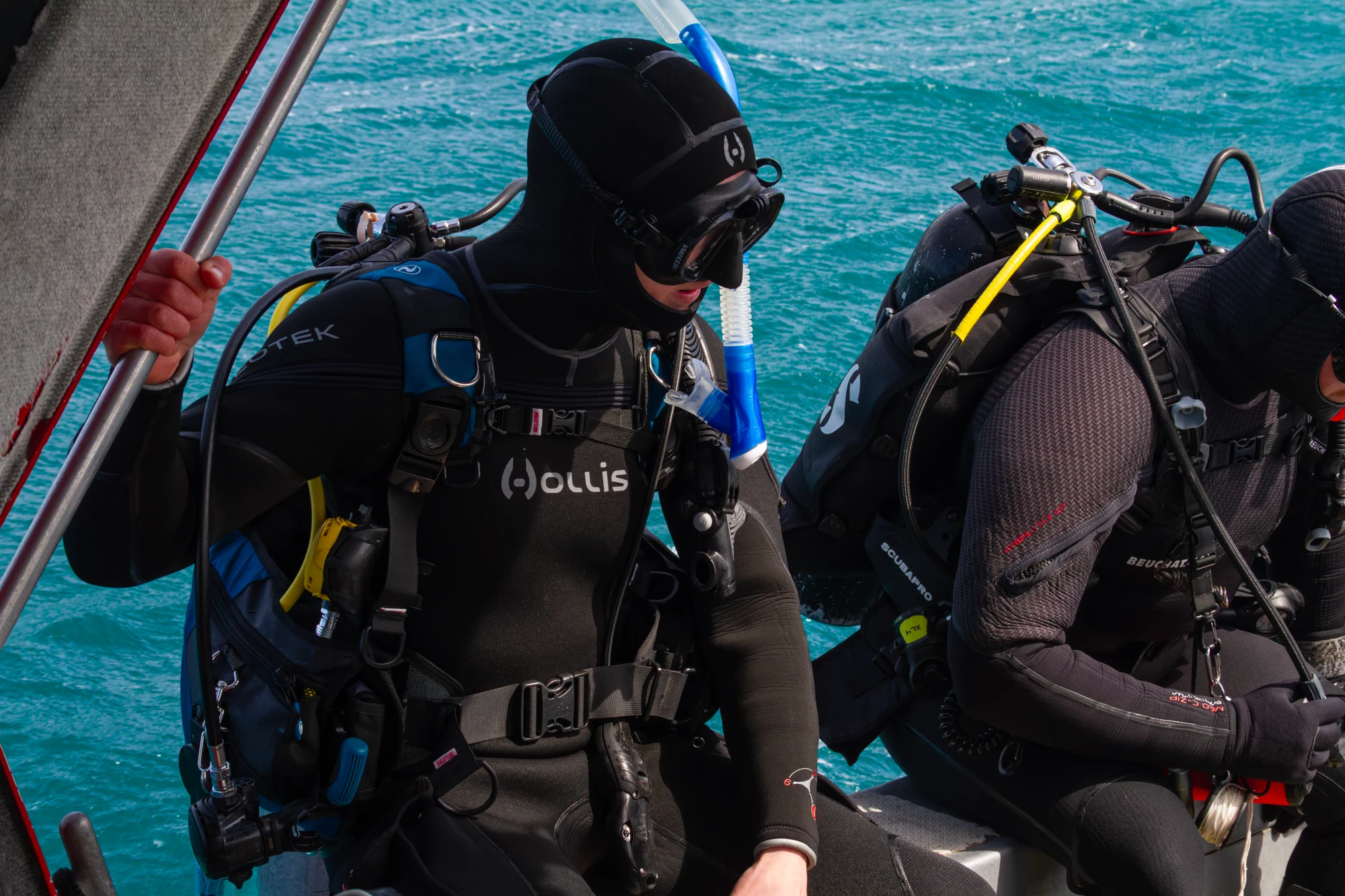 Divers prepare to enter the water from the side of their boat.