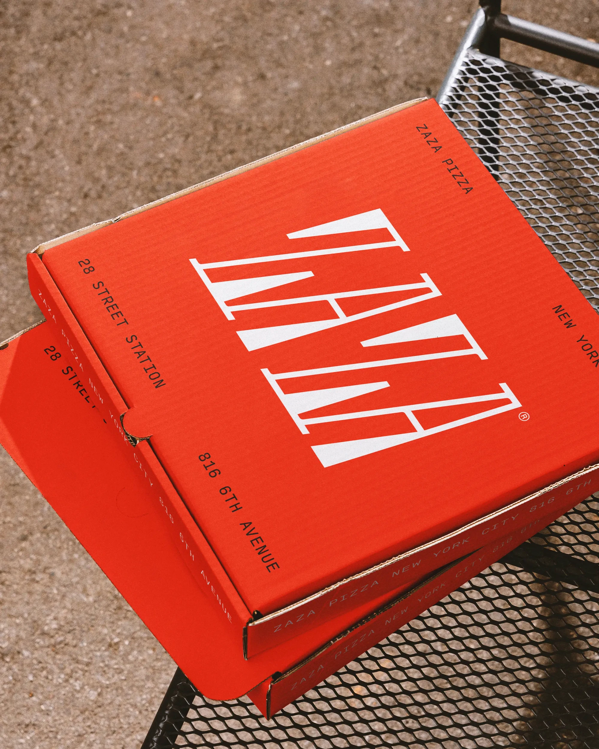 Branded red pizza boxes site stacked on a midtown bench.