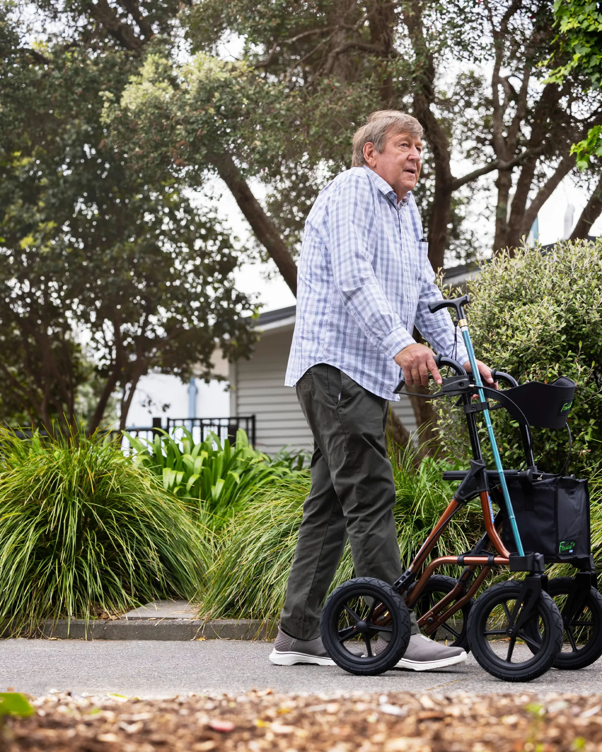 A senior man takes a stroll in the park using a walker.