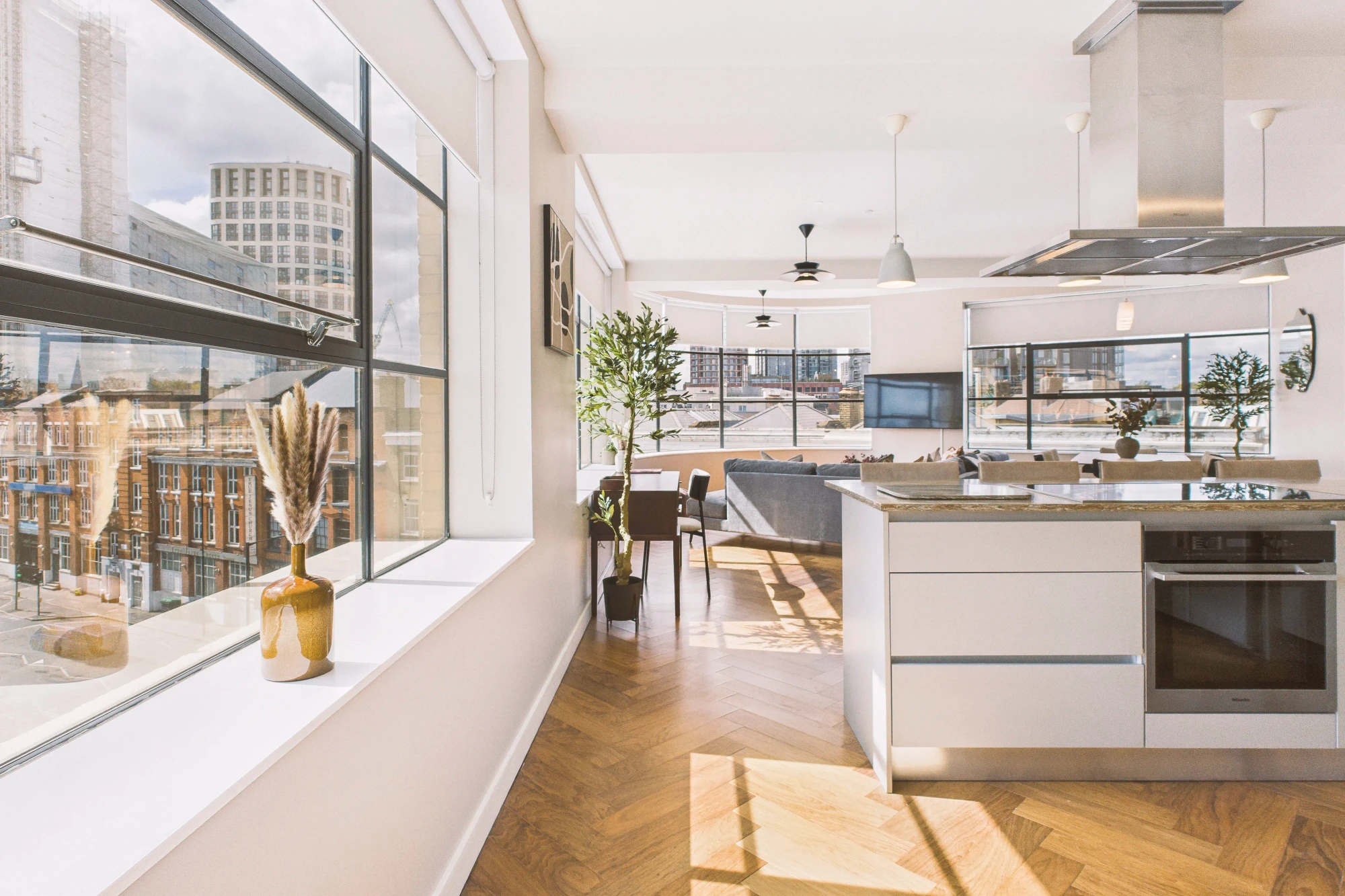 Sunlight streams through the windows of a beautiful white apartment.