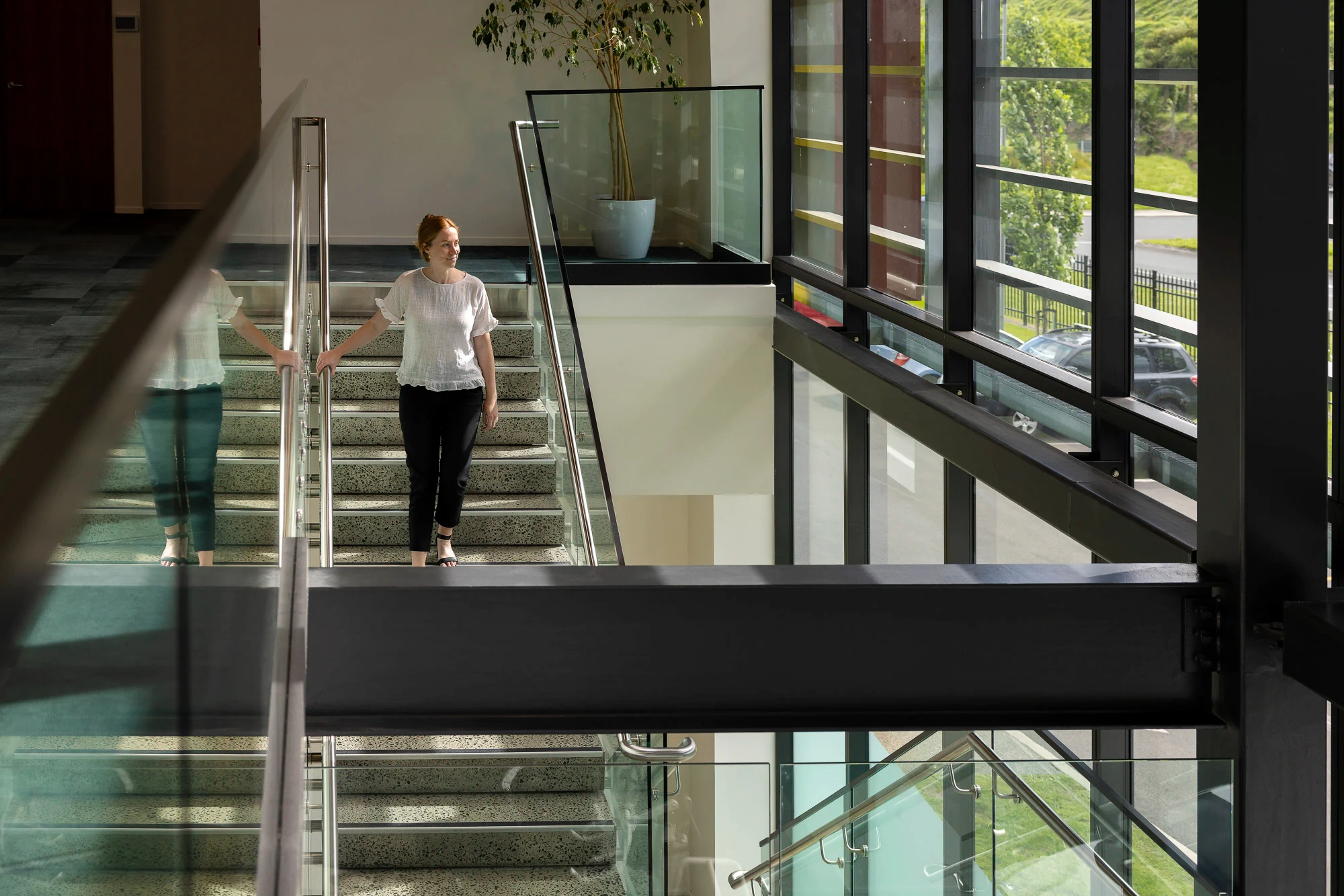 A woman descends a concrete and glass staircase at Cubro's headquarters.