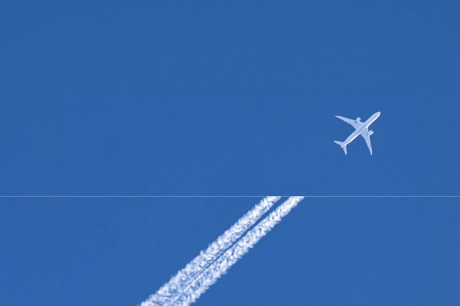 An aircraft contrail across a blue sky