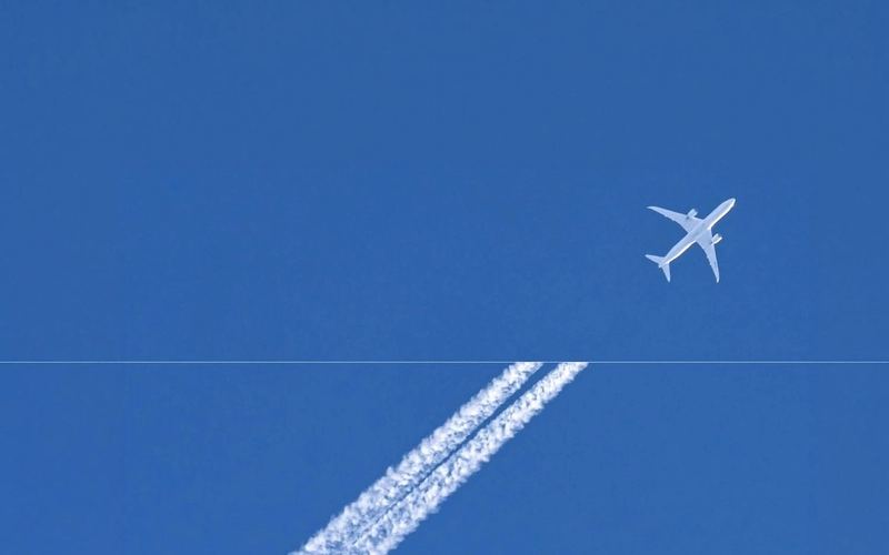 An aircraft contrail across a blue sky