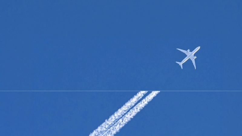 An aircraft contrail across a blue sky